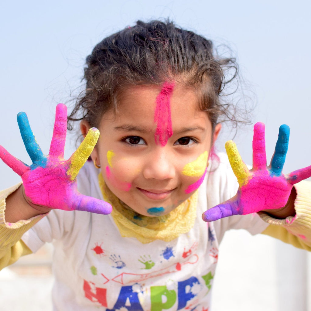 girl with brown hair and paint on her hands and face, very artistic