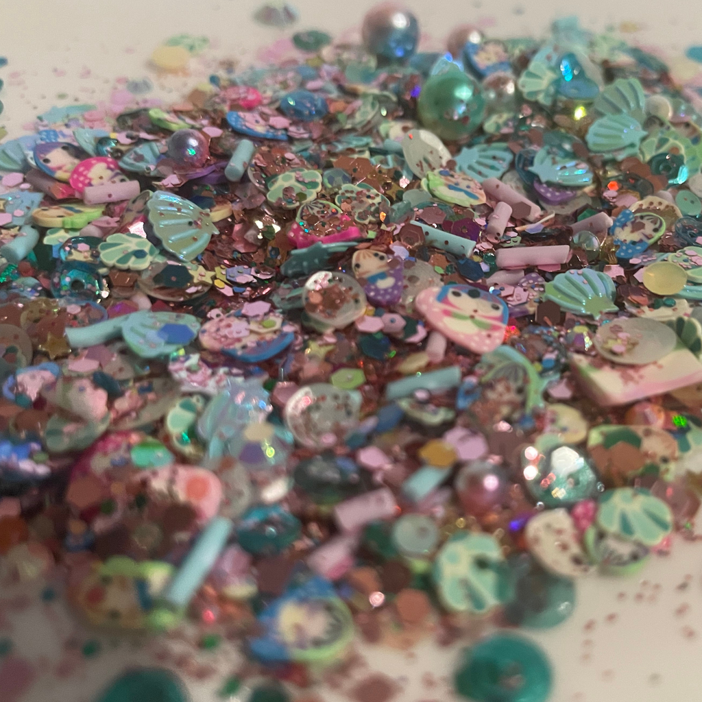 Colorful glittery mermaids, shells, sequins with various shapes and sizes on a white background