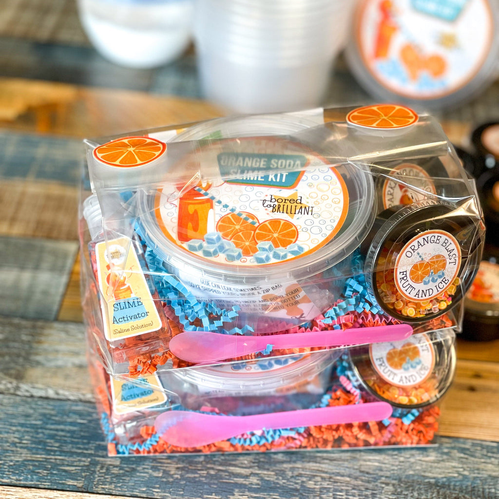 two orange soda slime kits already packaged, ready for shipment in clear containers with all diy kit ingredients in smaller containers in the package with labels for everything