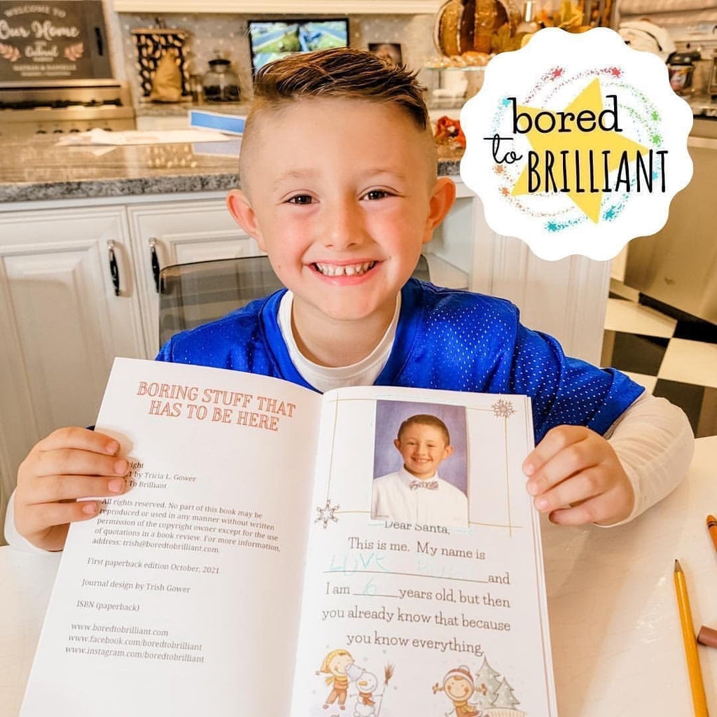smiling boy holding open the best santa ever book by kids showing he has personalized it