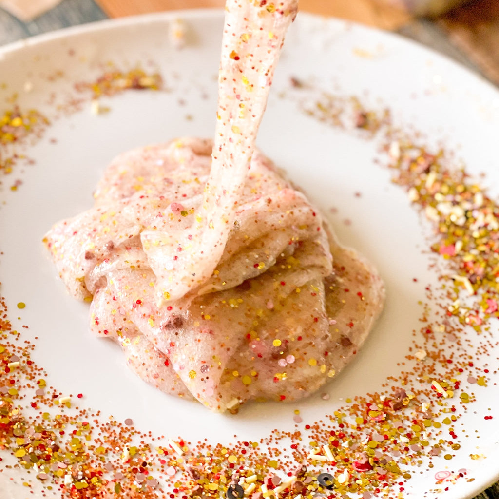 pizza slime that smells like pizza being pored into a white plate with glitter for this diy kit